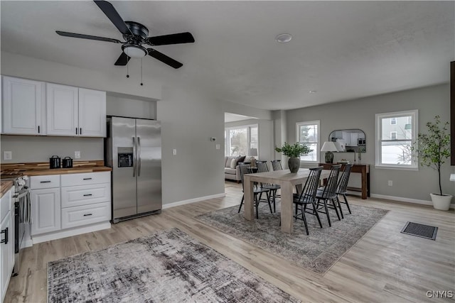 dining space with light wood-type flooring, visible vents, baseboards, and a wealth of natural light