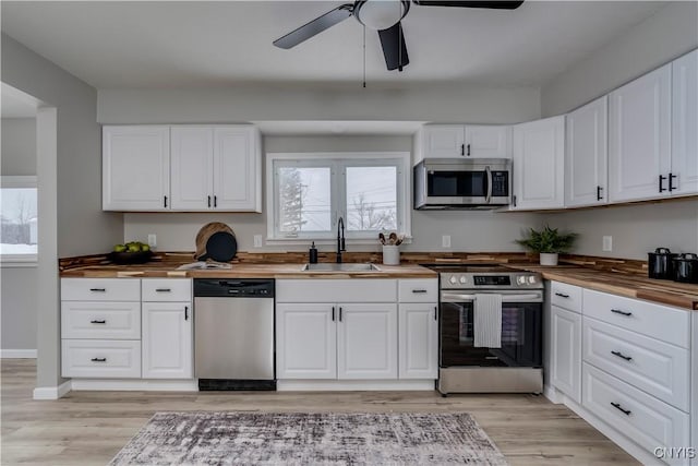 kitchen with light wood-style flooring, wood counters, appliances with stainless steel finishes, and a sink