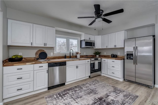 kitchen with light wood-style flooring, appliances with stainless steel finishes, wooden counters, and a sink