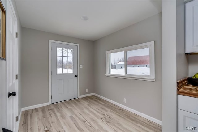 doorway to outside with light wood-style flooring and baseboards