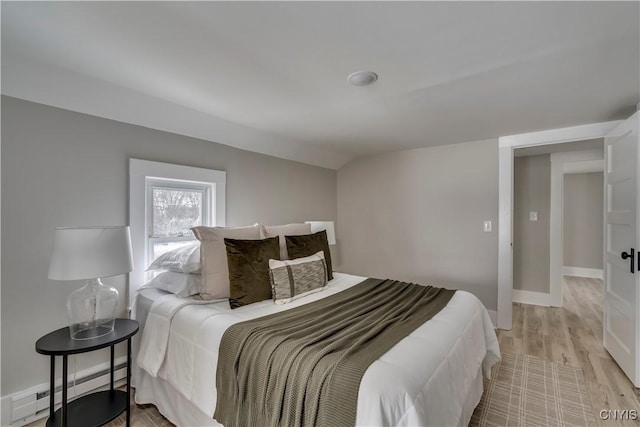 bedroom featuring light wood-type flooring, baseboards, and baseboard heating