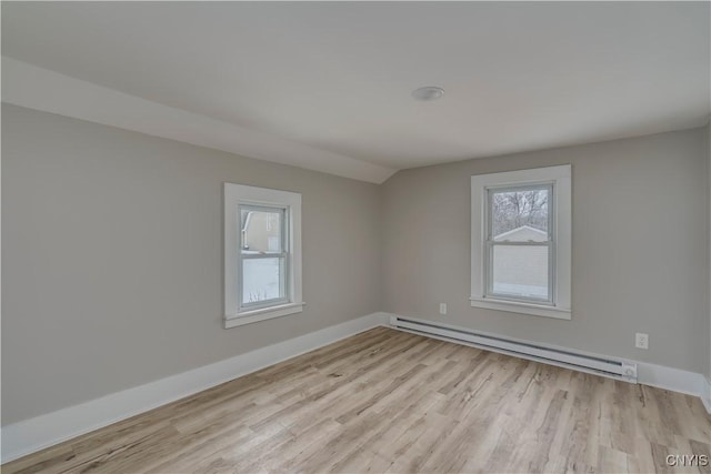 empty room featuring a baseboard radiator, baseboards, vaulted ceiling, and light wood finished floors