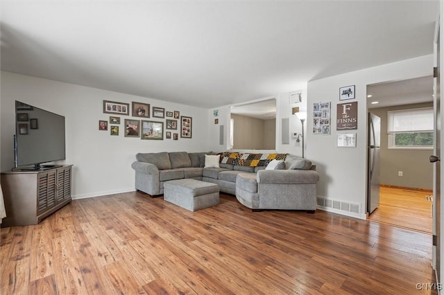 living area with wood-type flooring, visible vents, and baseboards