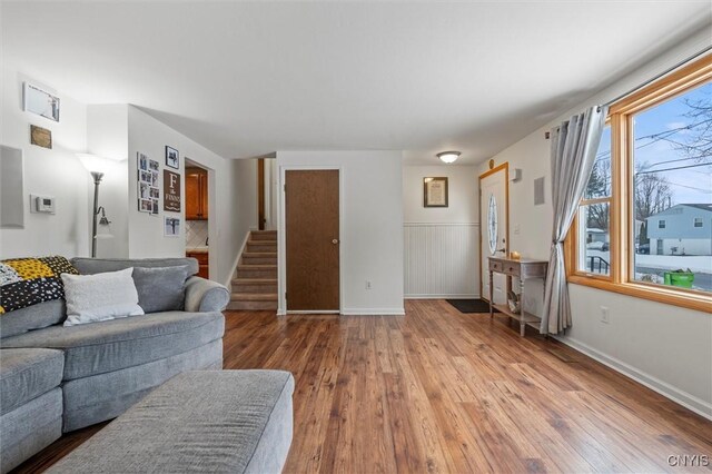 living room with baseboards, stairway, hardwood / wood-style floors, and wainscoting