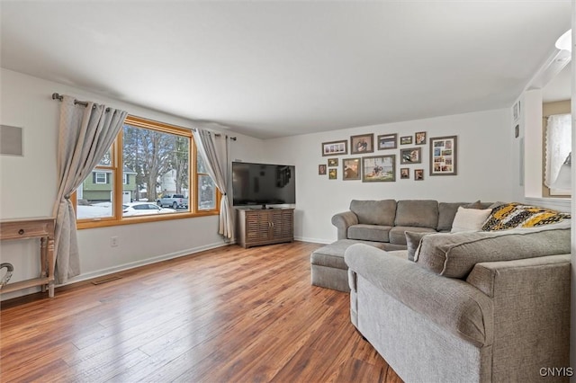 living room with visible vents, baseboards, and wood finished floors