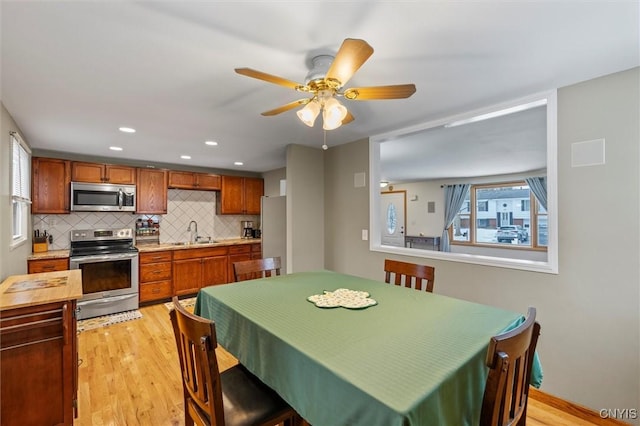 kitchen featuring light wood finished floors, stainless steel appliances, tasteful backsplash, light countertops, and a sink