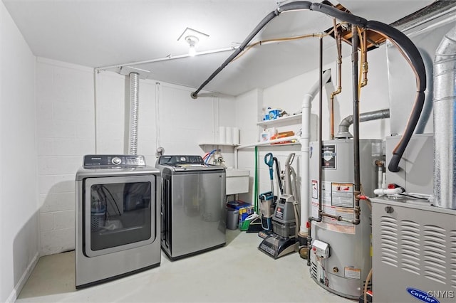 laundry area with water heater, laundry area, washing machine and dryer, and concrete block wall