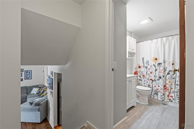 bathroom with toilet, a shower with curtain, wood finished floors, and vanity