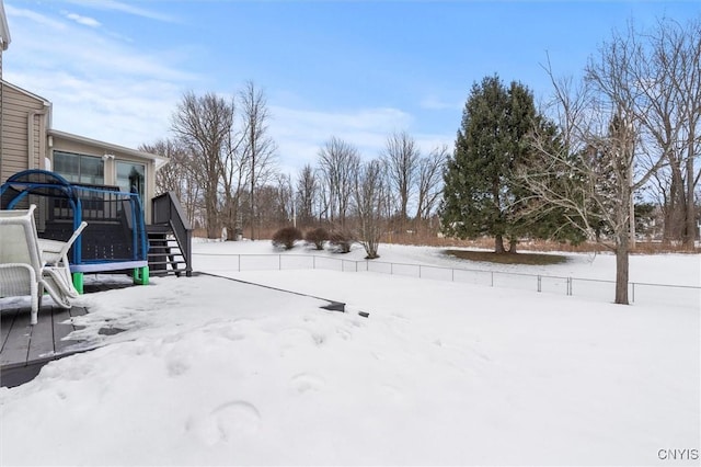 snowy yard with stairs, fence, and a deck