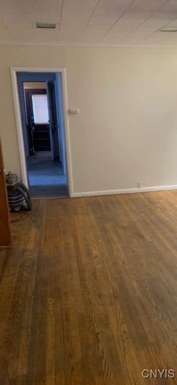 empty room featuring visible vents, baseboards, and wood finished floors