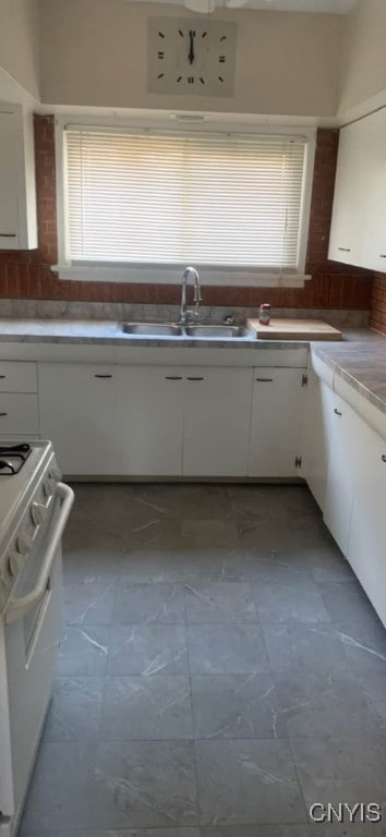 kitchen with gas range gas stove, a sink, white cabinetry, and decorative backsplash