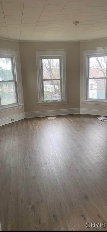 unfurnished room with wood finished floors, visible vents, and baseboards