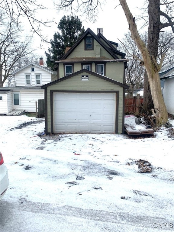 view of front of home with a garage, an outdoor structure, and fence