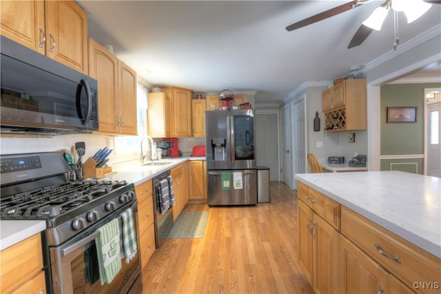 kitchen featuring light countertops, appliances with stainless steel finishes, a sink, and crown molding