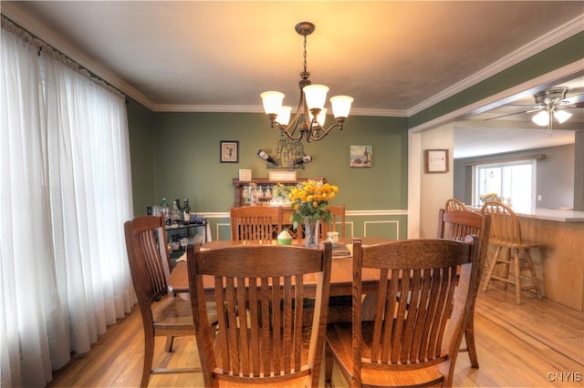 dining area with ornamental molding, light wood finished floors, and ceiling fan with notable chandelier