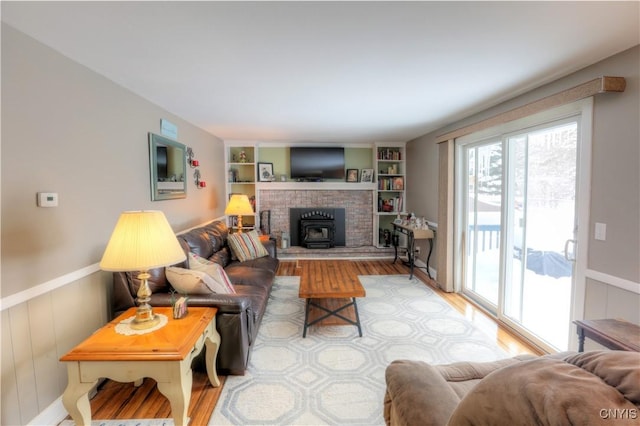 living area featuring a wainscoted wall, built in shelves, and wood finished floors