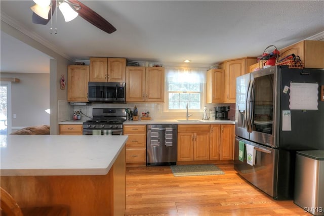 kitchen with plenty of natural light, appliances with stainless steel finishes, light countertops, light wood-style floors, and a sink