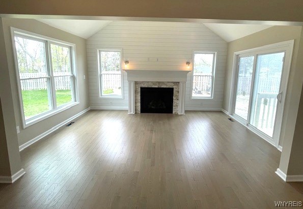 unfurnished living room with a fireplace with flush hearth, baseboards, wood finished floors, and lofted ceiling