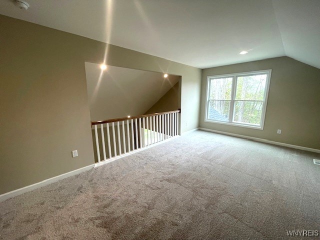 additional living space with baseboards, carpet, lofted ceiling, and visible vents