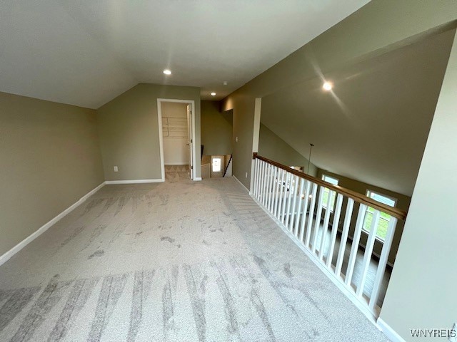 additional living space featuring carpet floors, baseboards, and lofted ceiling