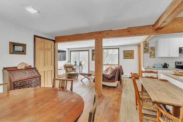 dining area featuring light wood-type flooring and beam ceiling