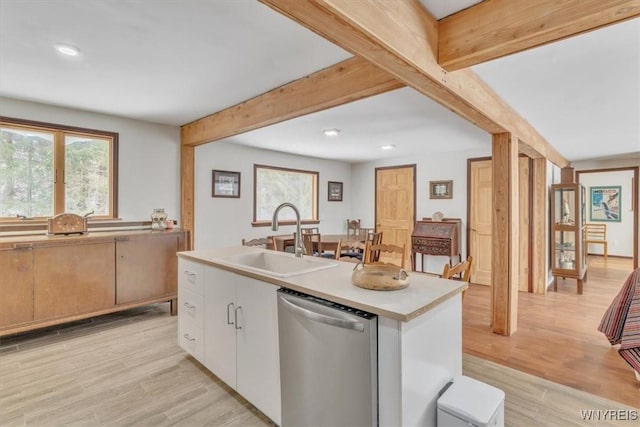 kitchen with a sink, light wood-style flooring, beam ceiling, and dishwasher