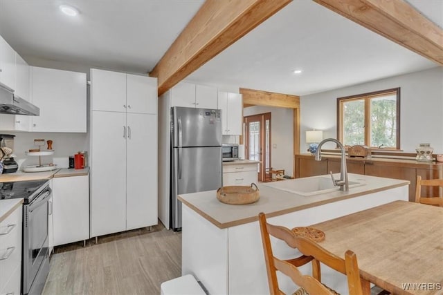 kitchen with a sink, light countertops, appliances with stainless steel finishes, light wood finished floors, and beamed ceiling