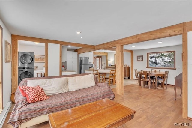 living room featuring recessed lighting, light wood-style flooring, stacked washer / dryer, and beamed ceiling