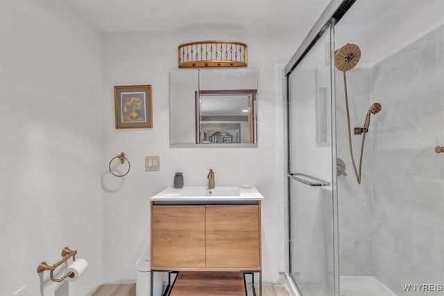 full bath featuring a stall shower, vanity, and wood finished floors