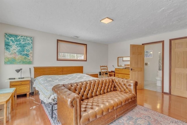 bedroom featuring ensuite bath, a textured ceiling, and hardwood / wood-style floors