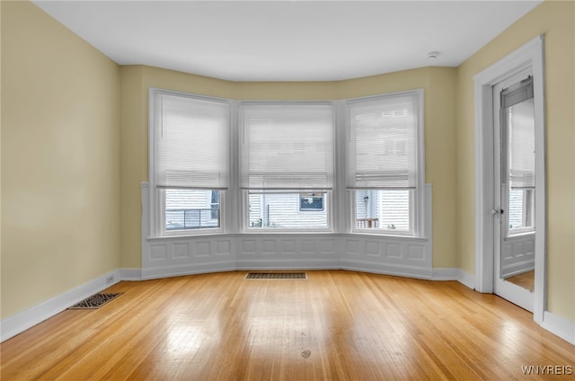 empty room featuring a healthy amount of sunlight, light wood-style flooring, and visible vents