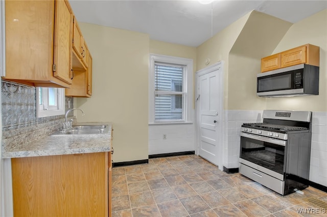 kitchen featuring light brown cabinets, a sink, baseboards, light countertops, and appliances with stainless steel finishes