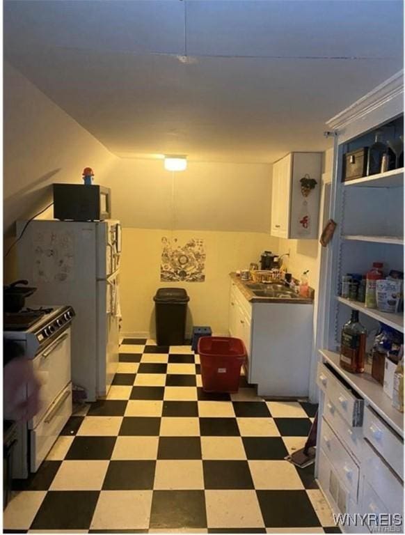 kitchen featuring light floors, gas range oven, and white cabinetry