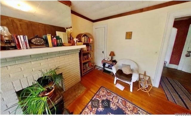 sitting room with ornamental molding, a fireplace, and wood finished floors