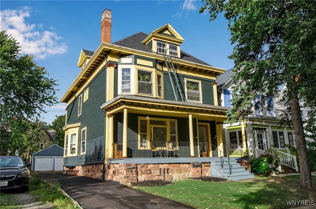 view of front facade with covered porch, a chimney, an outdoor structure, and a detached garage