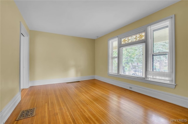 empty room featuring light wood finished floors, visible vents, and baseboards