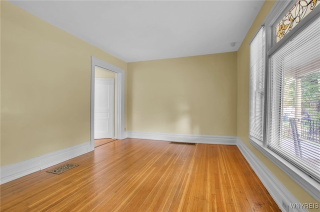 spare room with light wood finished floors, visible vents, and baseboards