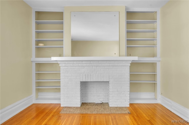 details with built in shelves, a fireplace, baseboards, and wood finished floors