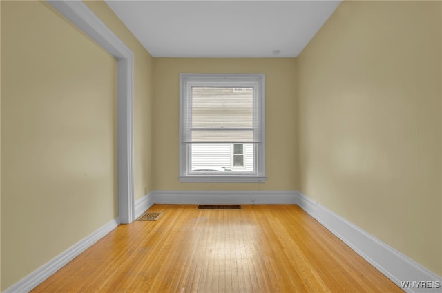 empty room featuring light wood-style flooring, visible vents, and baseboards