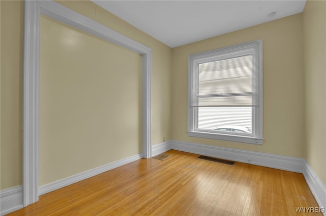 unfurnished room featuring light wood-type flooring, visible vents, and baseboards