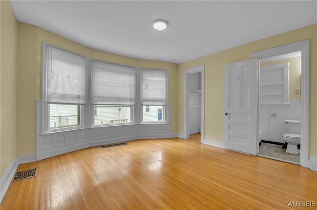 unfurnished bedroom featuring light wood-type flooring, baseboards, visible vents, and a closet