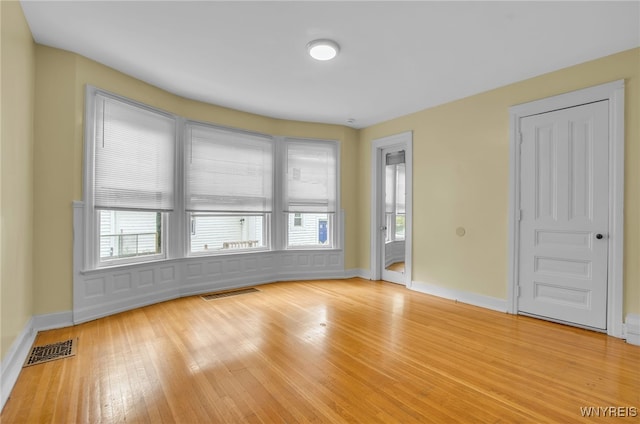 spare room with light wood-type flooring, baseboards, and visible vents