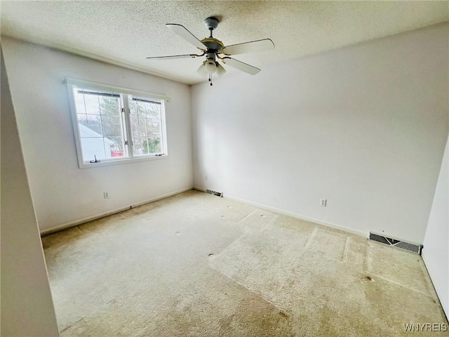 spare room with carpet, visible vents, a ceiling fan, a textured ceiling, and baseboards