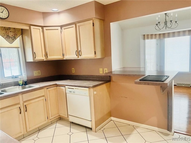 kitchen featuring a peninsula, a sink, visible vents, dishwasher, and an inviting chandelier