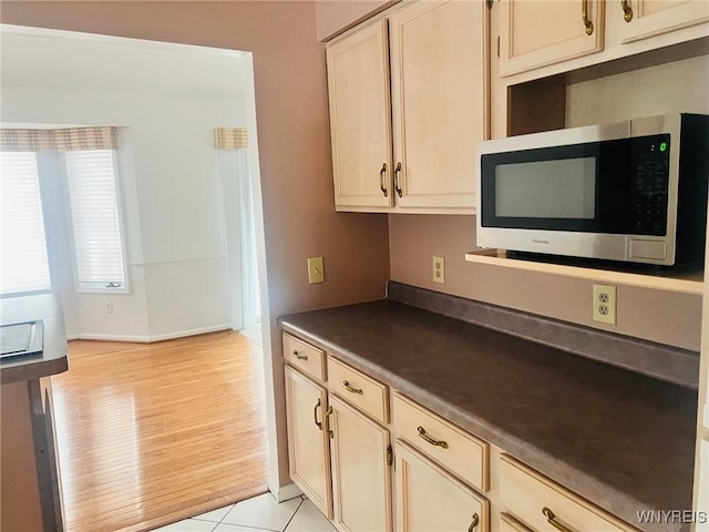 kitchen featuring light tile patterned floors, stainless steel microwave, and dark countertops