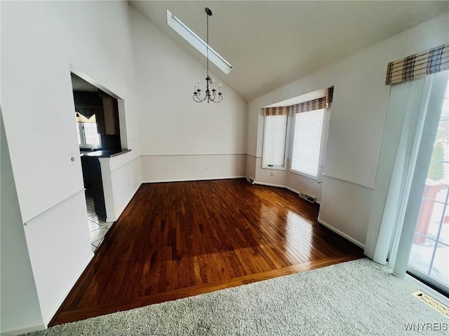 unfurnished dining area with high vaulted ceiling, visible vents, a notable chandelier, and wood finished floors