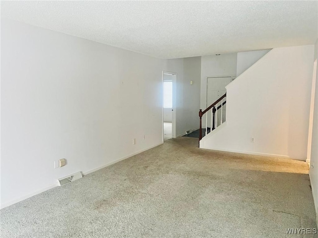 unfurnished room featuring visible vents, baseboards, stairway, carpet, and a textured ceiling