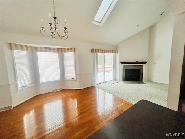 unfurnished living room with a skylight, visible vents, hardwood / wood-style floors, and a tiled fireplace