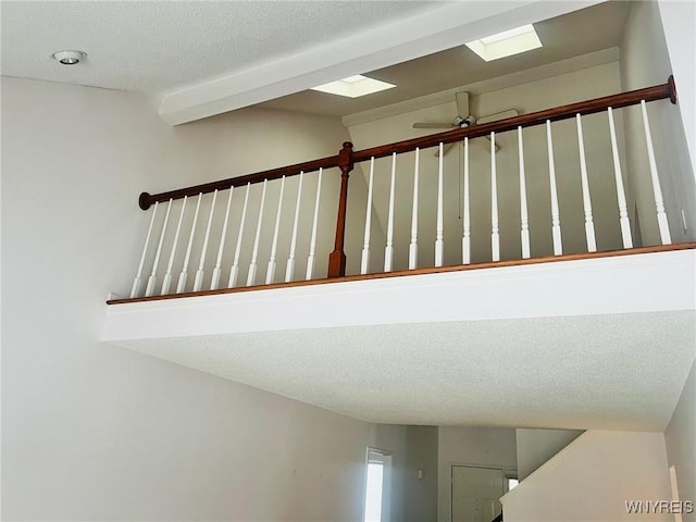 stairs with a textured ceiling and ceiling fan