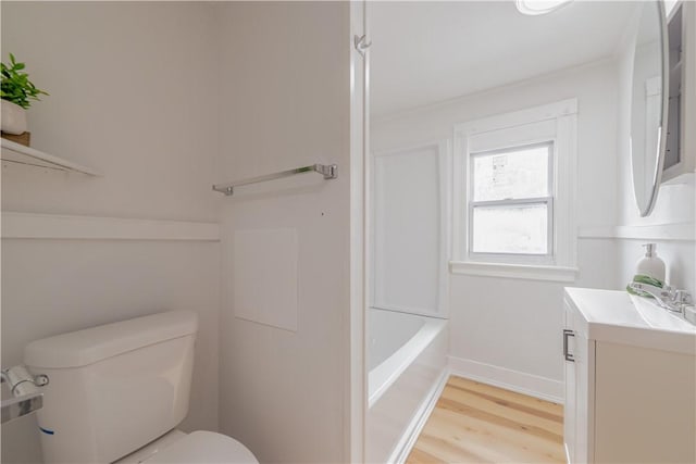 bathroom featuring toilet, baseboards, wood finished floors, and vanity